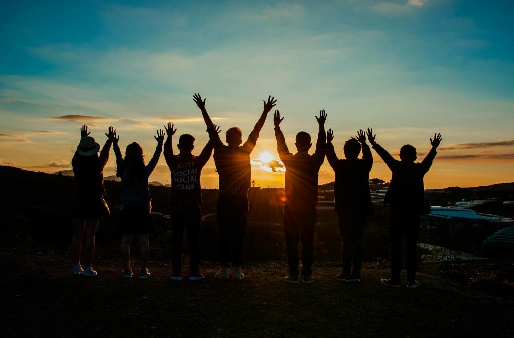 A group of people with their hands in the air at a sunset - representing support